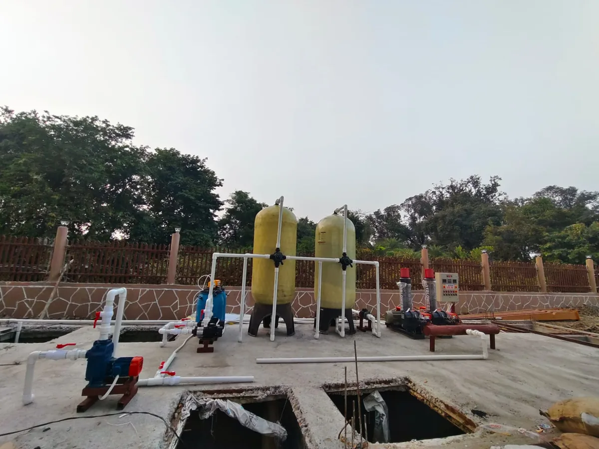 Completed commercial sewage treatment plant showing underground civil tanks, twin air blowers, and tertiary FRP filter columns